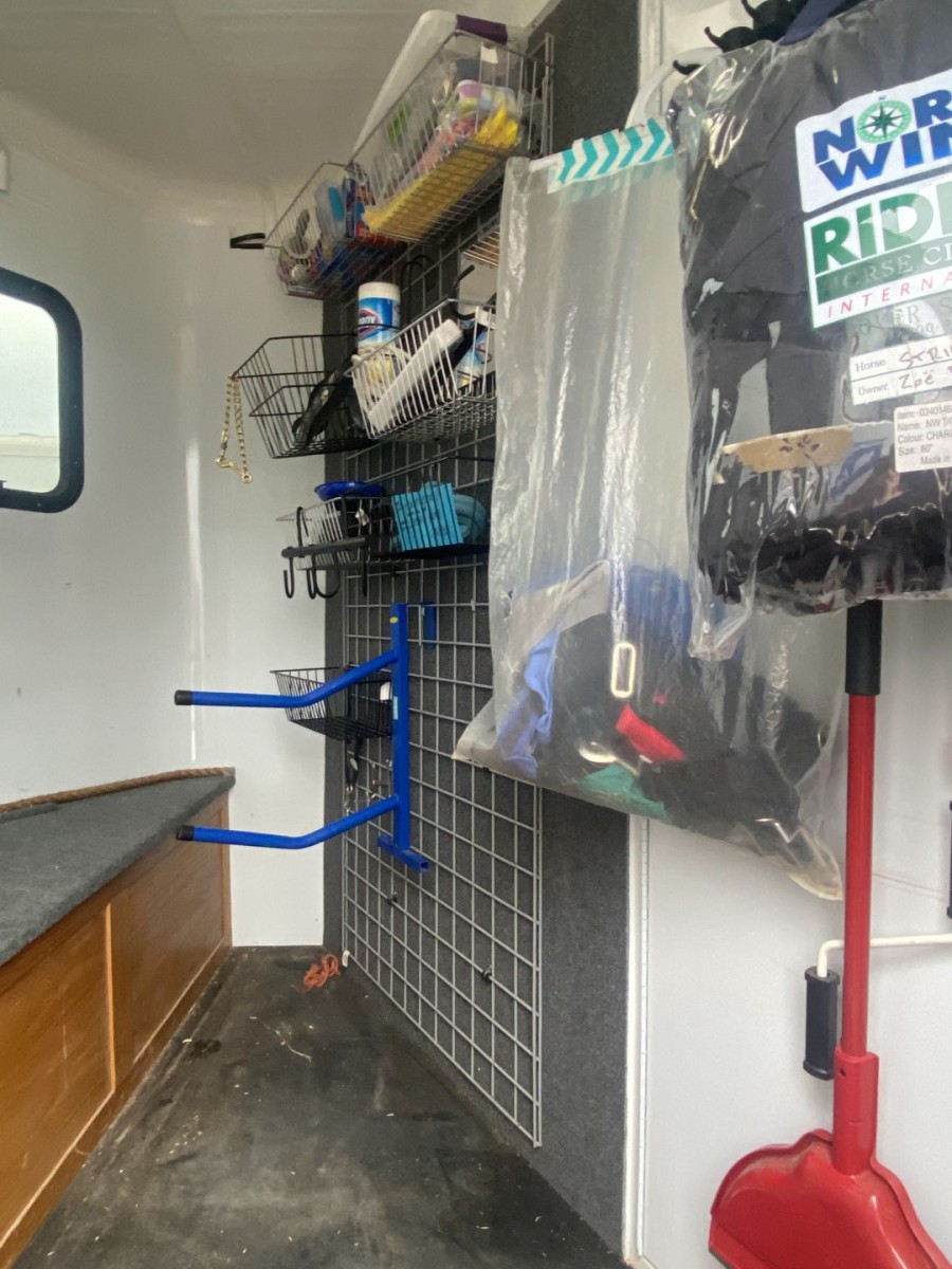 A wall grid organizer with tack and supplies inside of a Double D Trailer,