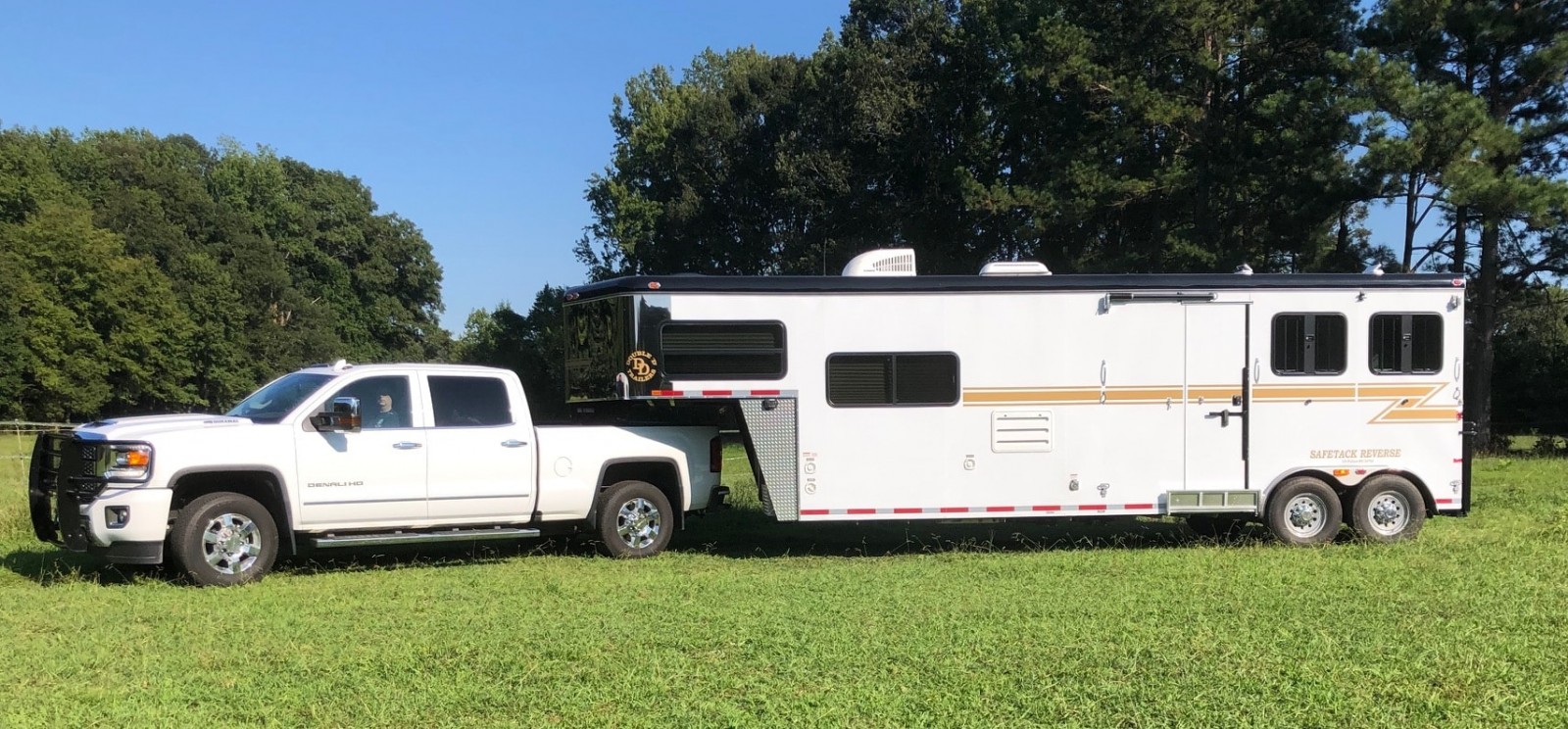 A Double D Trailers horse trailer with living quarters hitched to a tow vehicle. 