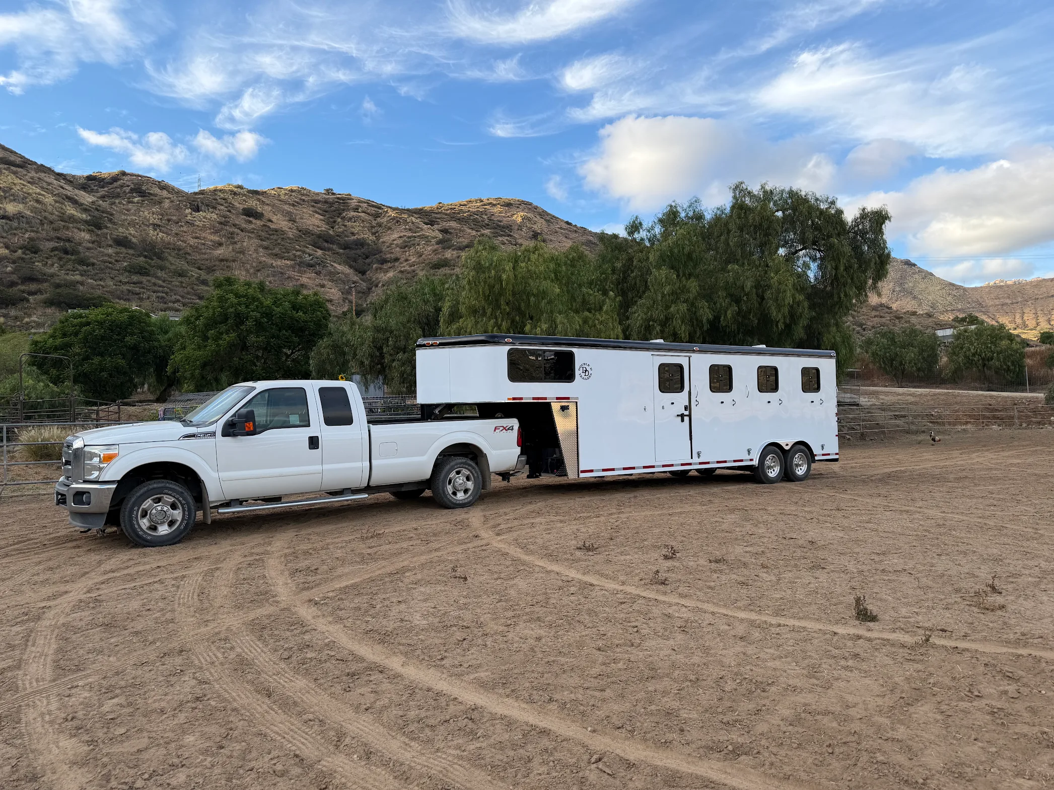 A Double D gooseneck trailer hitched to the owner's truck in the hills