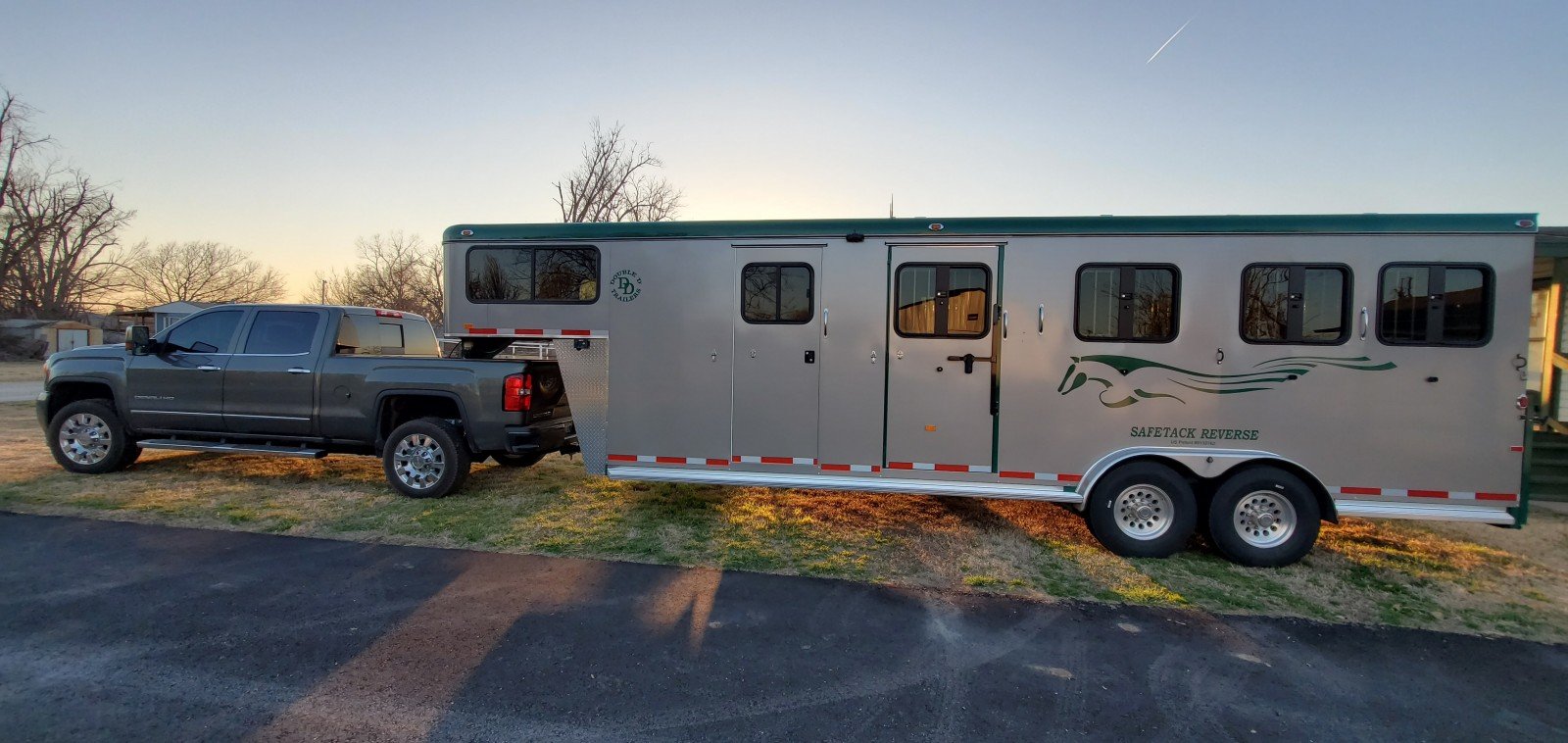 A Double D gooseneck horse trailer hitched to a tow vehicle.