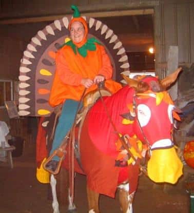 Horse dressed in a turkey costume with faux feathers and rider in a Thanksgiving-themed outfit.