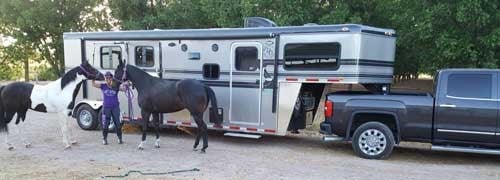 A Double D Gooseneck Trailer owner posing with her 2 horses while hitched up to her tow truck. 
