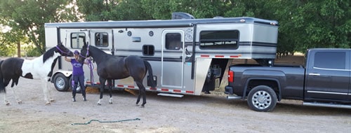 A Double D Trailers gooseneck trailer owner posed with her horses in front of the trailer. 