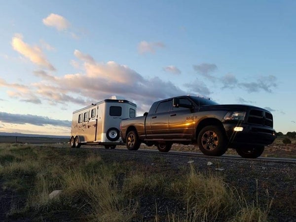 A Double D Trailers horse trailer parked and hitched to a tow truck.