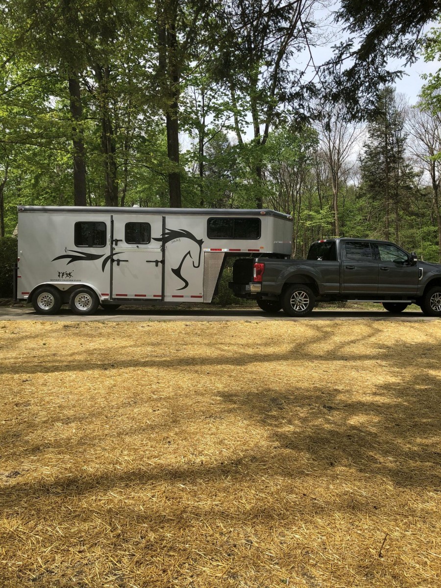 grey truck parked with a grey gooseneck horse trailer attached