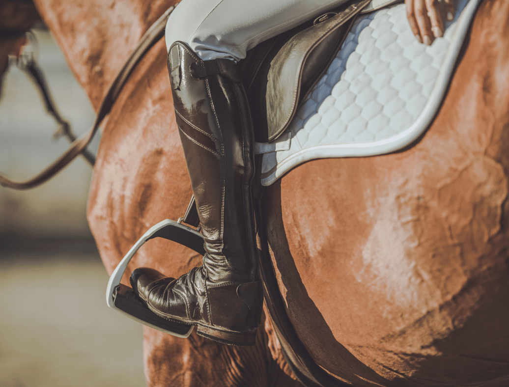 a photo of a rider on a horse; only showing the riders leg and boots and the side of the horse