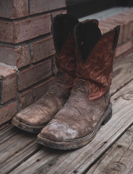 a pair of brown cowboy boots sitting outside on a front porch
