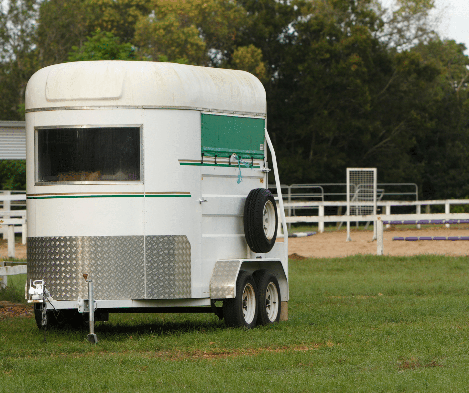a small bumper pull trailer parked in an open grass lot
