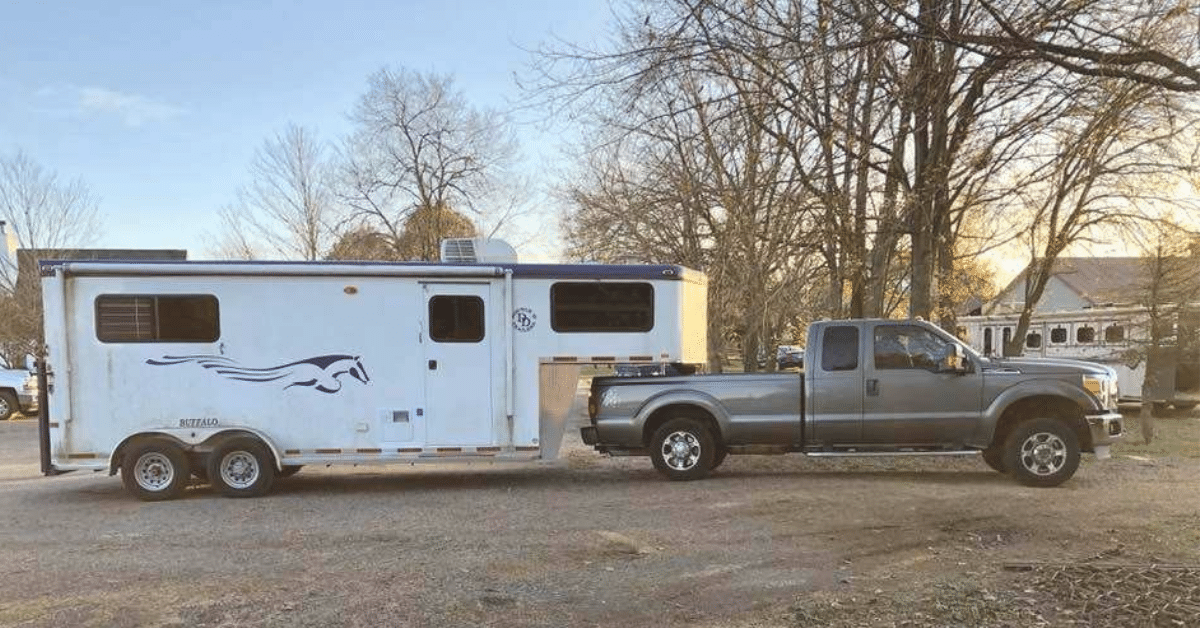 A Double D Trailers gooseneck horse trailer hitched to a tow truck