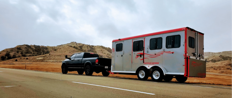 a bumper pull horse trailer being hauled down the road