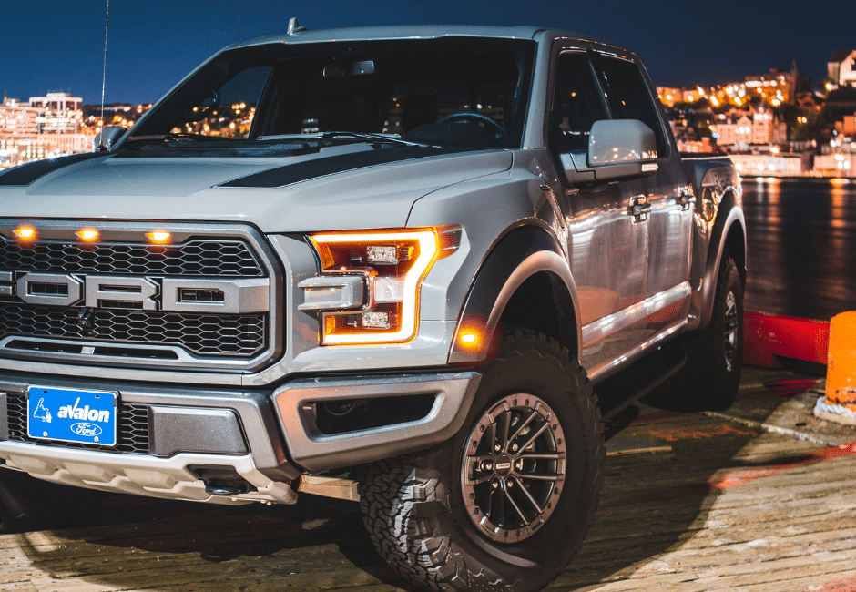 A Ford truck at nighttime with the lights turned on. 