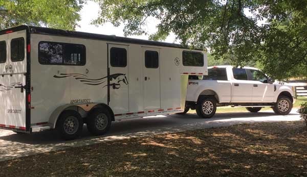 A Double D Trailers gooseneck model hooked up to a white truck as the tow vehicle.