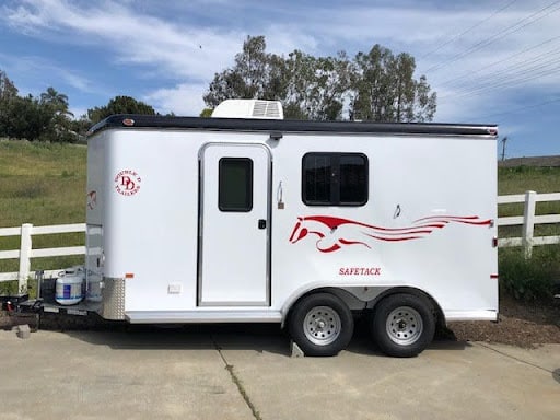  A Double D bumper pull horse trailer with red reflective decals for enhanced visibility on the road.