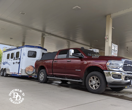 A Double D bumper pull horse trailer hitched to a Dodge tow truck.